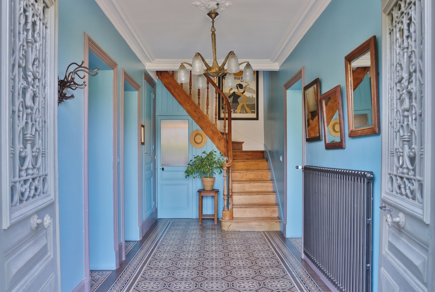 Entrée bleue en carreaux de ciment avec escalier en bois