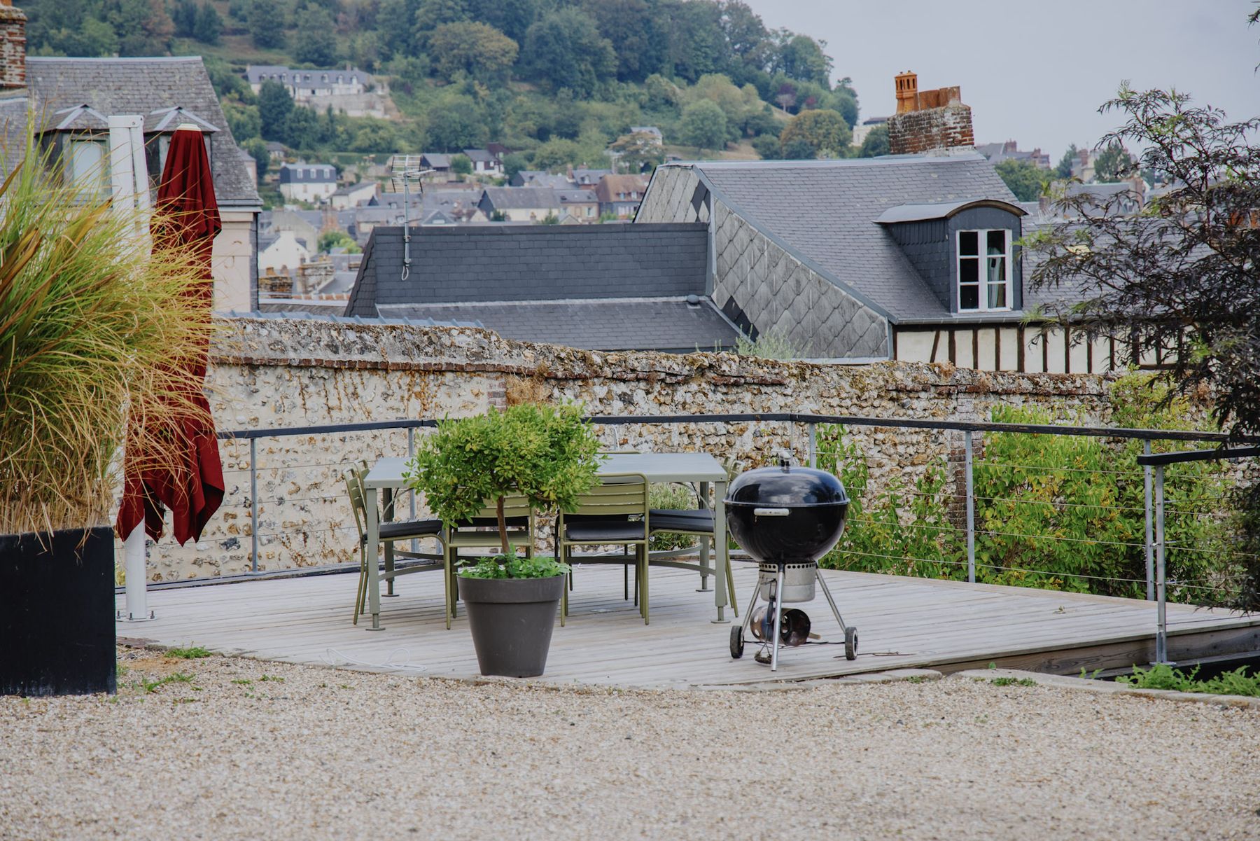 Terrasse en bois de la Villa Marguerite avec sa table, son barbecue Weber et les toits de Honfleur en contrebas